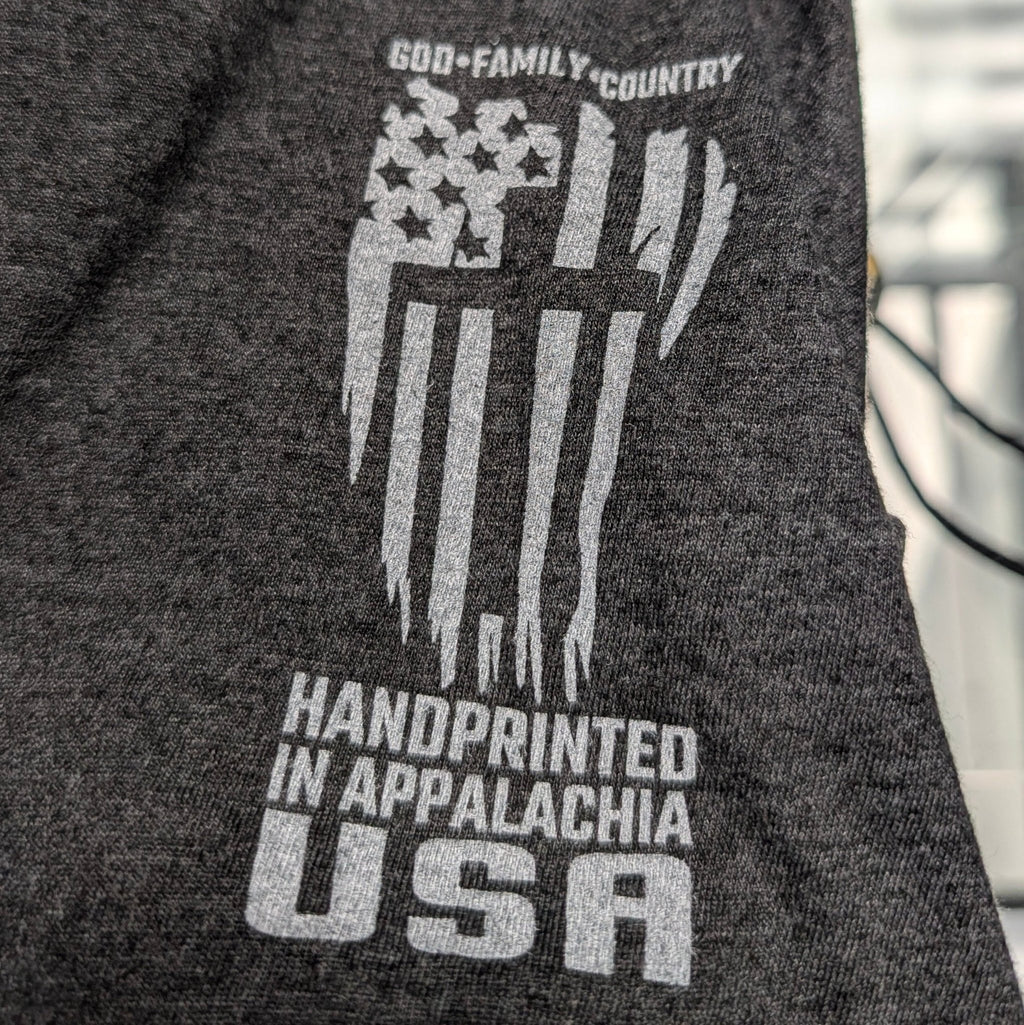 The "American Resolve" Premium Graphic Tee - Meridian EDC | Laserworks - Dark gray sweatshirt with white graphic and text on a blurred indoor background